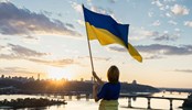 Sunset over the city of Kyiv. a woman holds a large waving Ukrainian flag standing high on the roof. Ukrainians are against war. Drawing attention to military actions in Ukraine. independence Day.